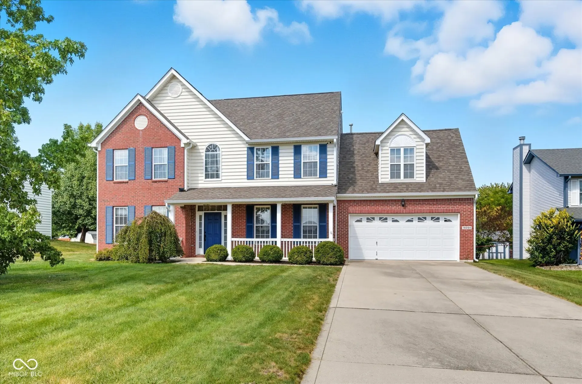 Two story brick home with blue shutters and a manicured front lawn in a Central Indiana neighborhood
